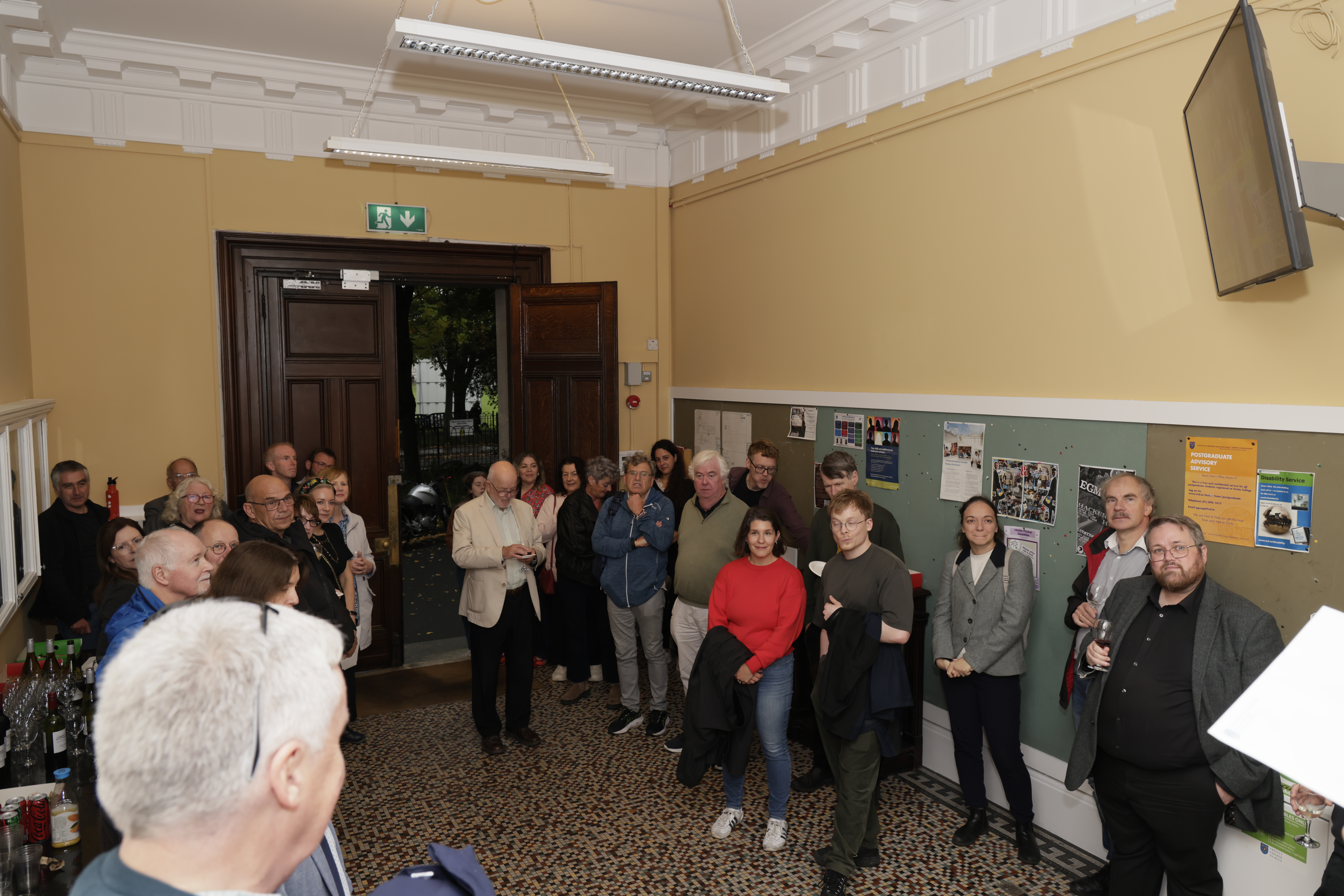 A group of Colleagues listen to the Head of School speak about the achievements of the retirees