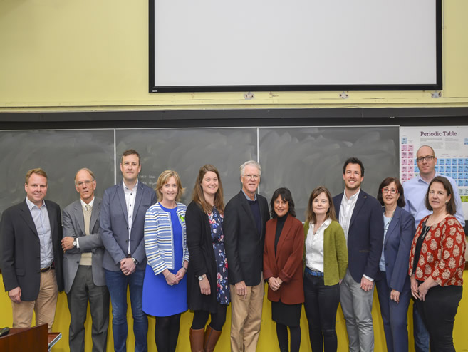 A group of Professors stand in front of a Lecture Theatre Blackboard